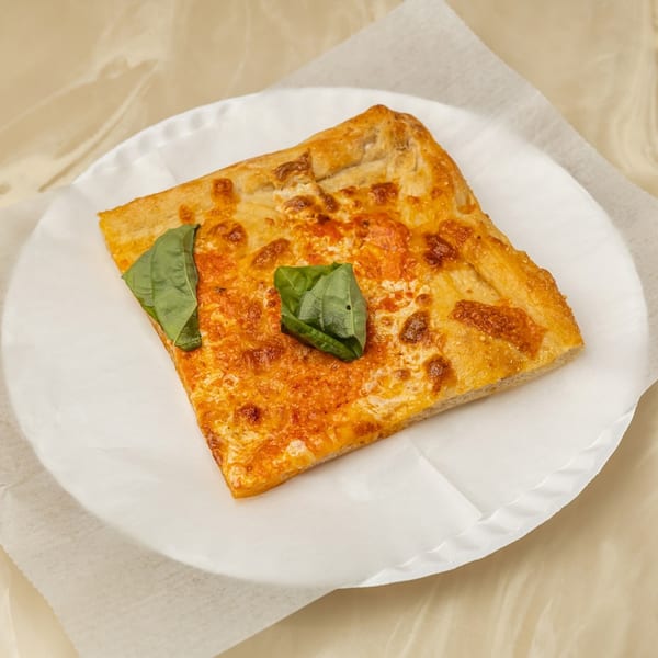 A square slice of Tori T's Pizzeria cheese pizza with basil on a white paper plate.