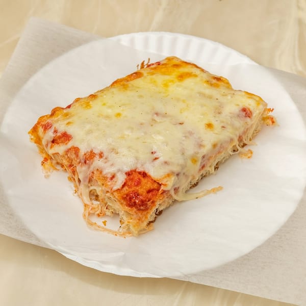 A thick, rectangular slice of Tori T's Pizzeria cheese pizza on a white paper plate.
