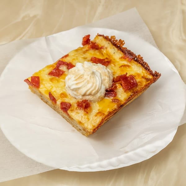 A square slice of Tori T's Pizzeria pizza with pepperoni and a dollop of ricotta cheese.